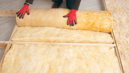 A shot of a man unrolling insulation on to a rooftop.