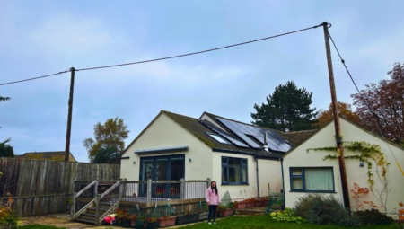 Wide view of a sustainable homeowner posing under solar panels.