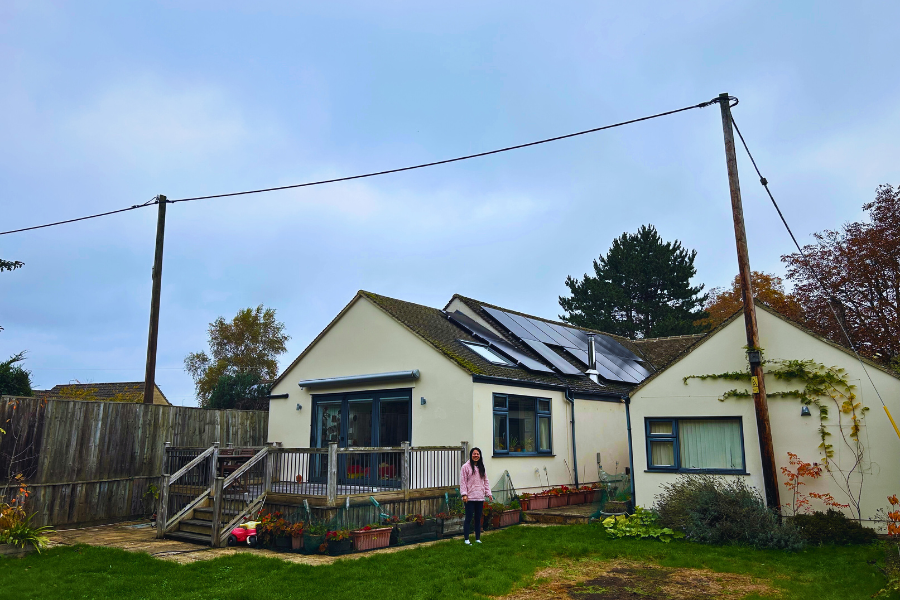 Wide view of a sustainable homeowner posing under solar panels.